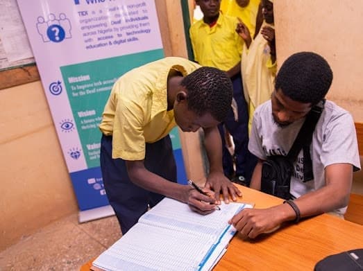 A TIDI mentor supporting a student with a written activity during a Kaduna program